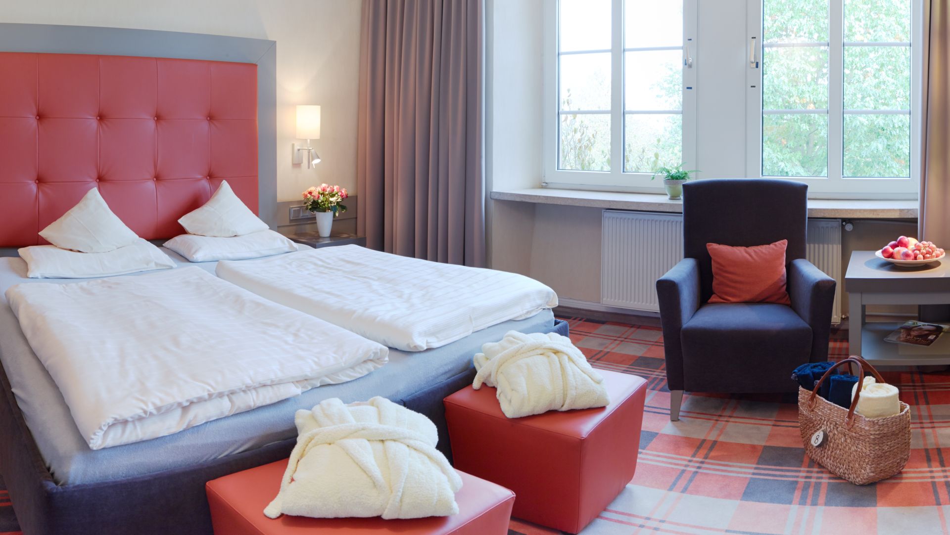 Cozy hotel room with red headboard, white bedding, and comfortable seating area