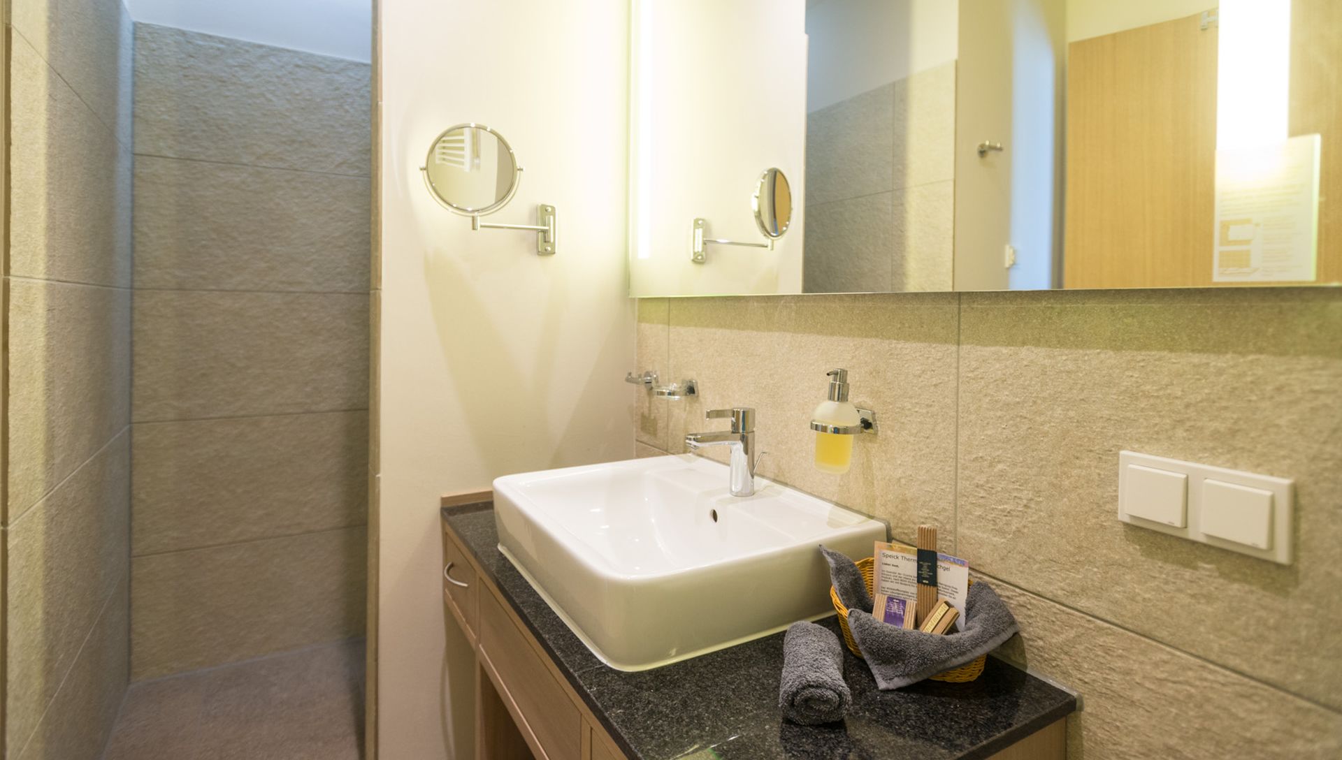 Modernes Badezimmer mit Waschbecken, großem Spiegel und Pflegeset