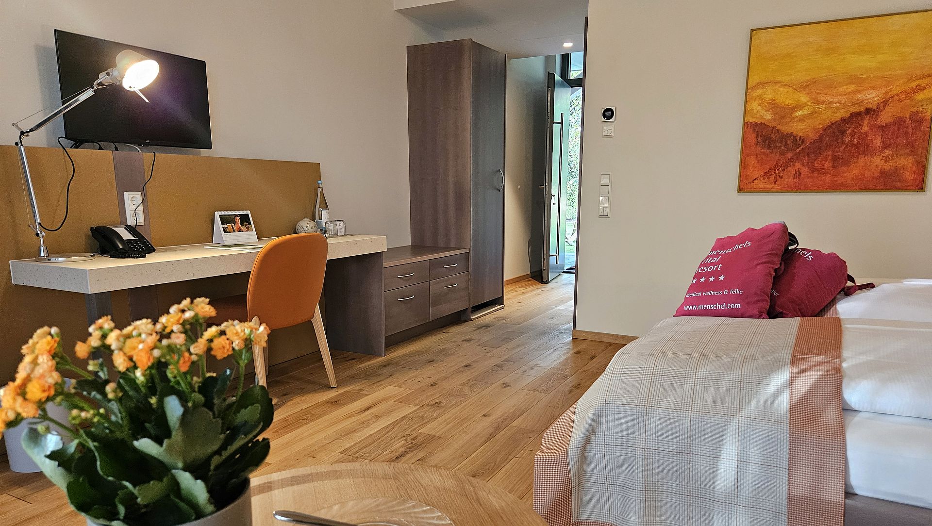 Modernes Hotelzimmer mit Schreibtisch, Blumen und gemütlichem Bett