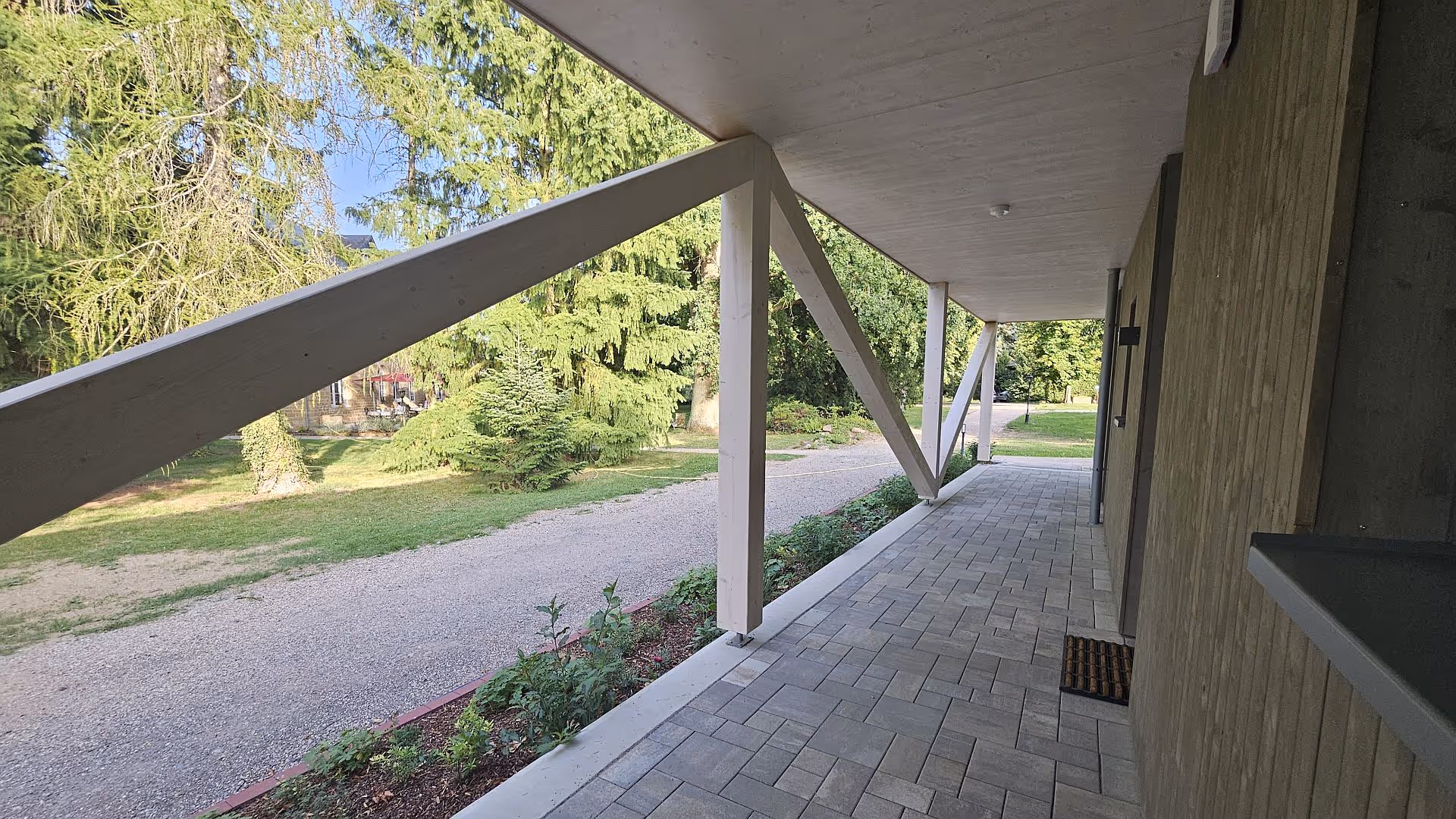 Covered porch with white supports overlooking green lawn and trees