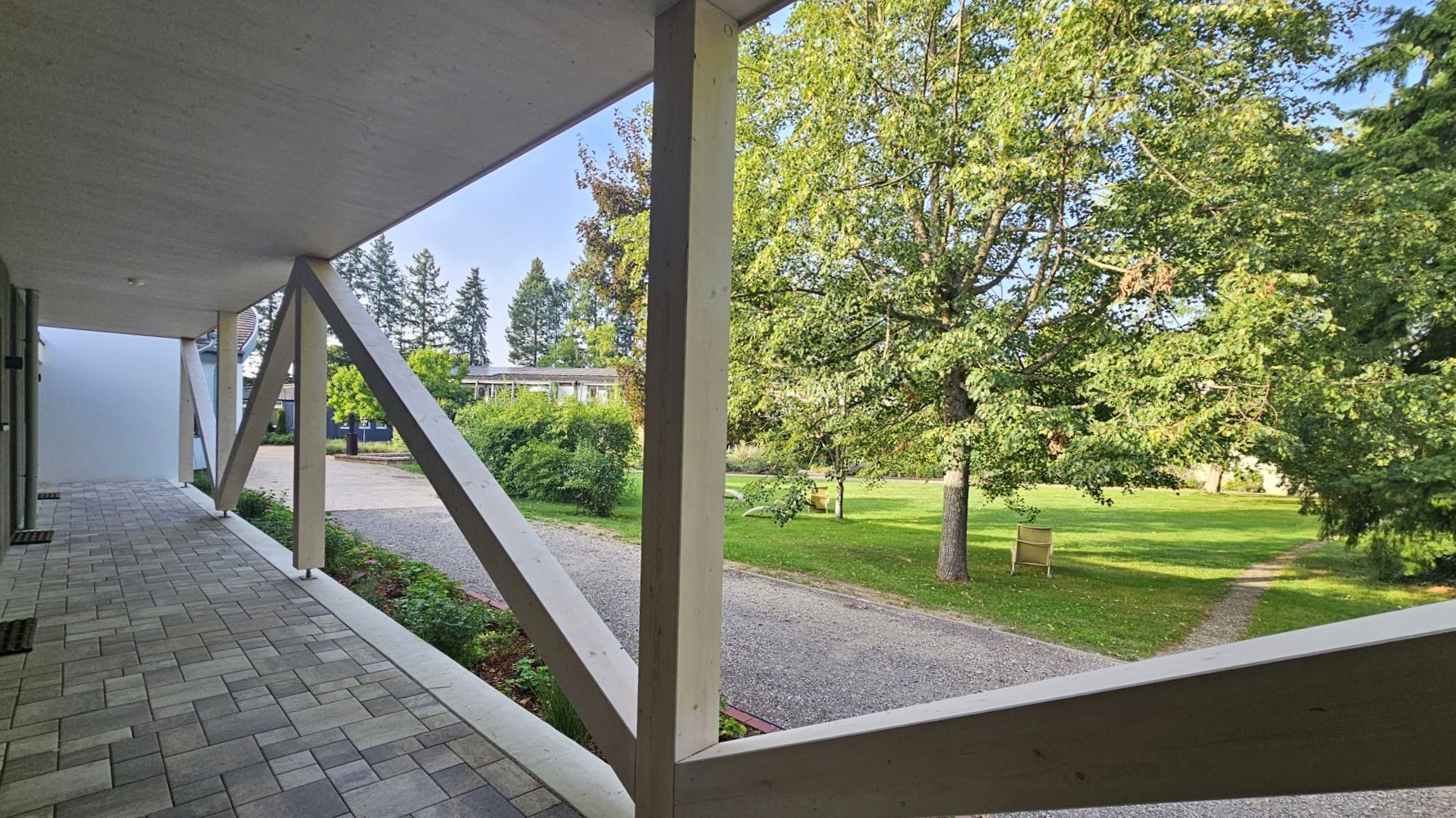Moderner überdachter Eingang mit Blick auf einen grünen Garten und Bäume
