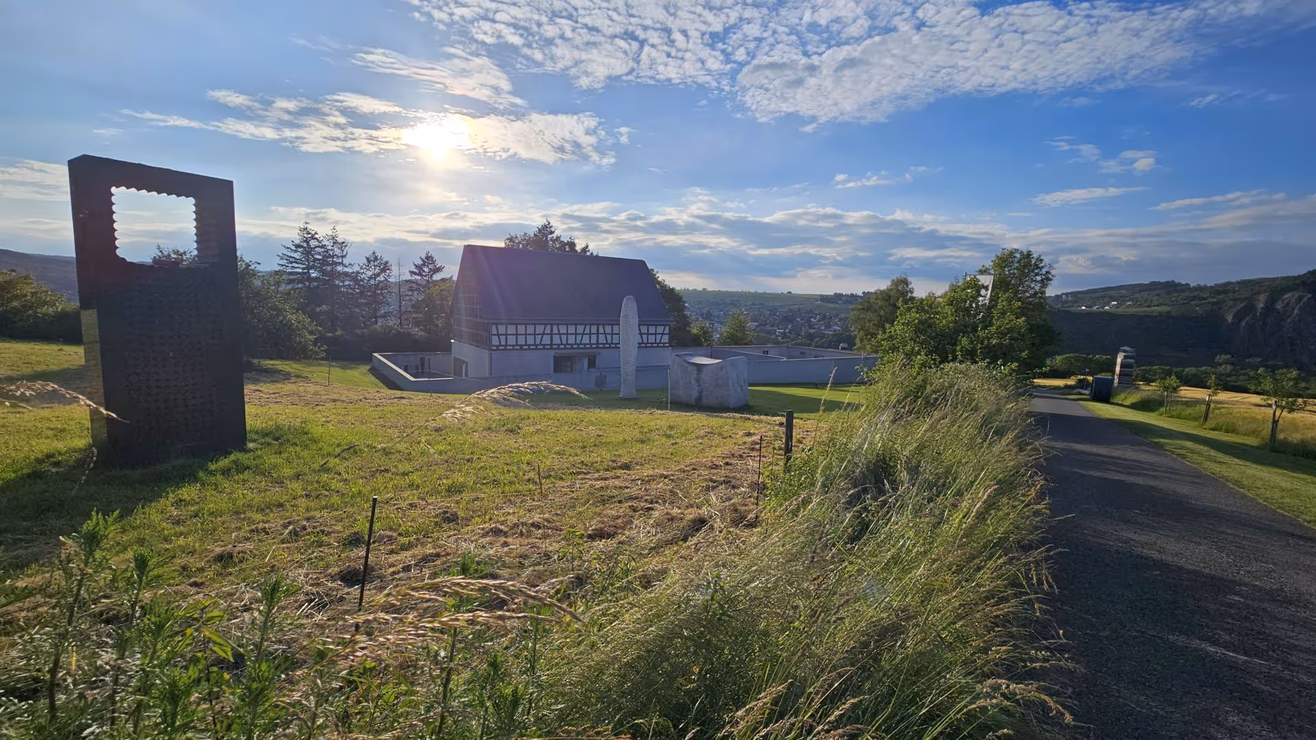 Half-timbered building and sculpture against cloudy sky and rural landscape