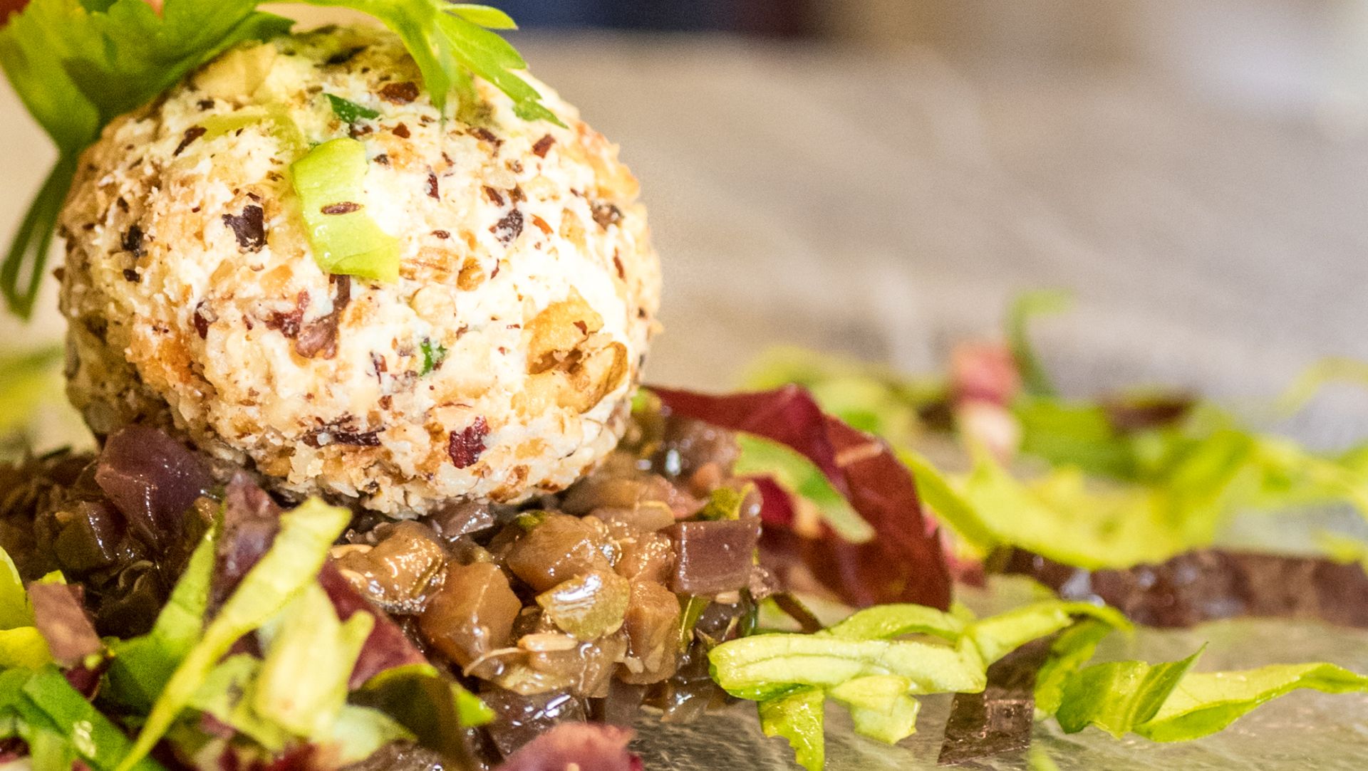 Savory cheese ball with herbs on bed of mixed salad greens