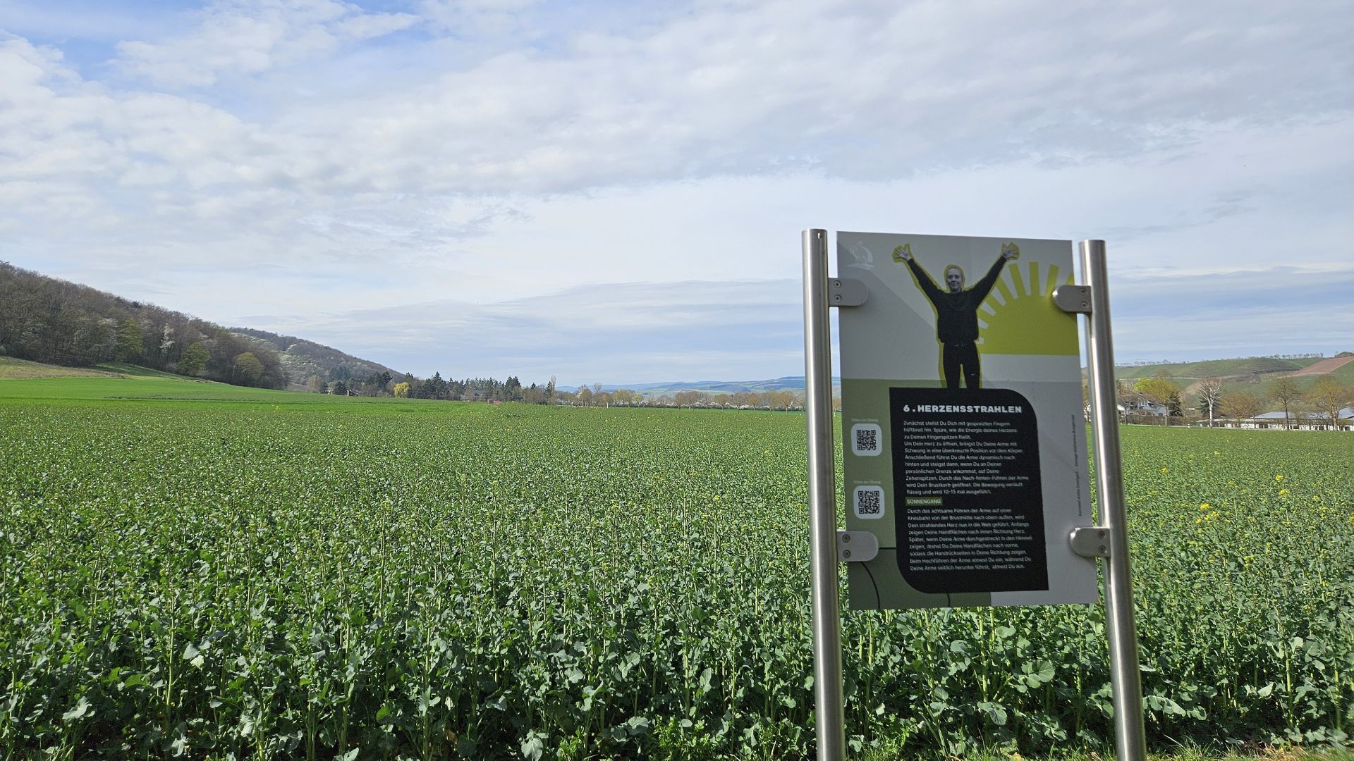 Informational sign in green field with hills and cloudy sky background