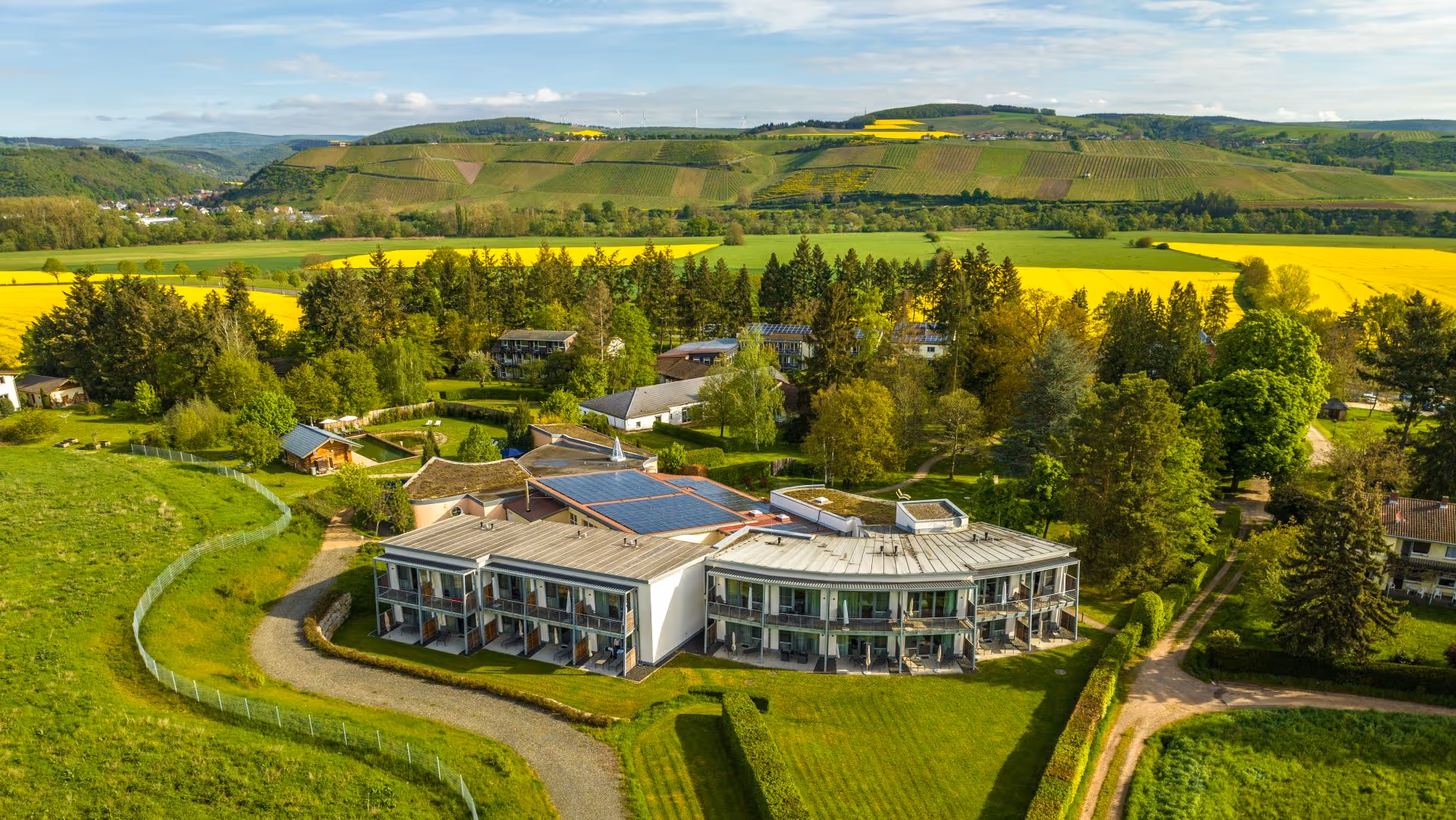 Moderne Wohnanlage umgeben von grünen Hügeln und gelben Rapsfeldern