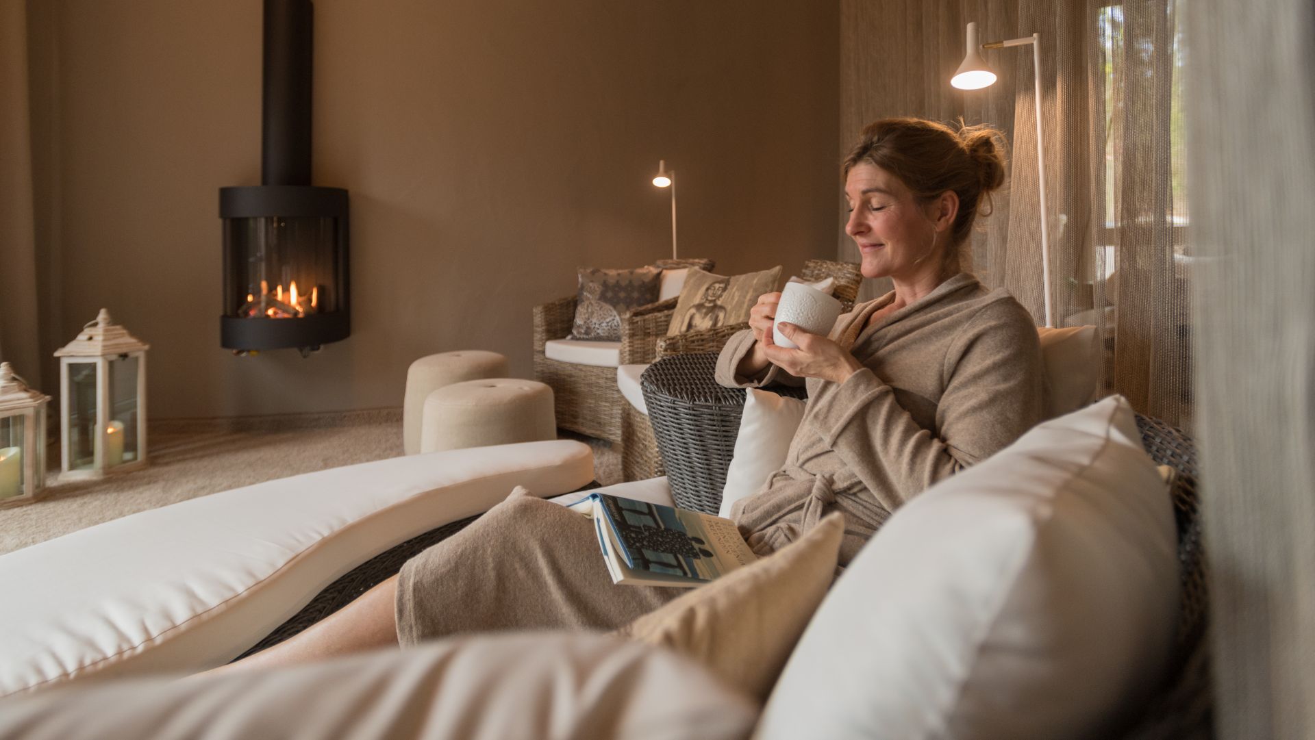 Woman relaxing with coffee by fireplace, enjoying a cozy peaceful moment