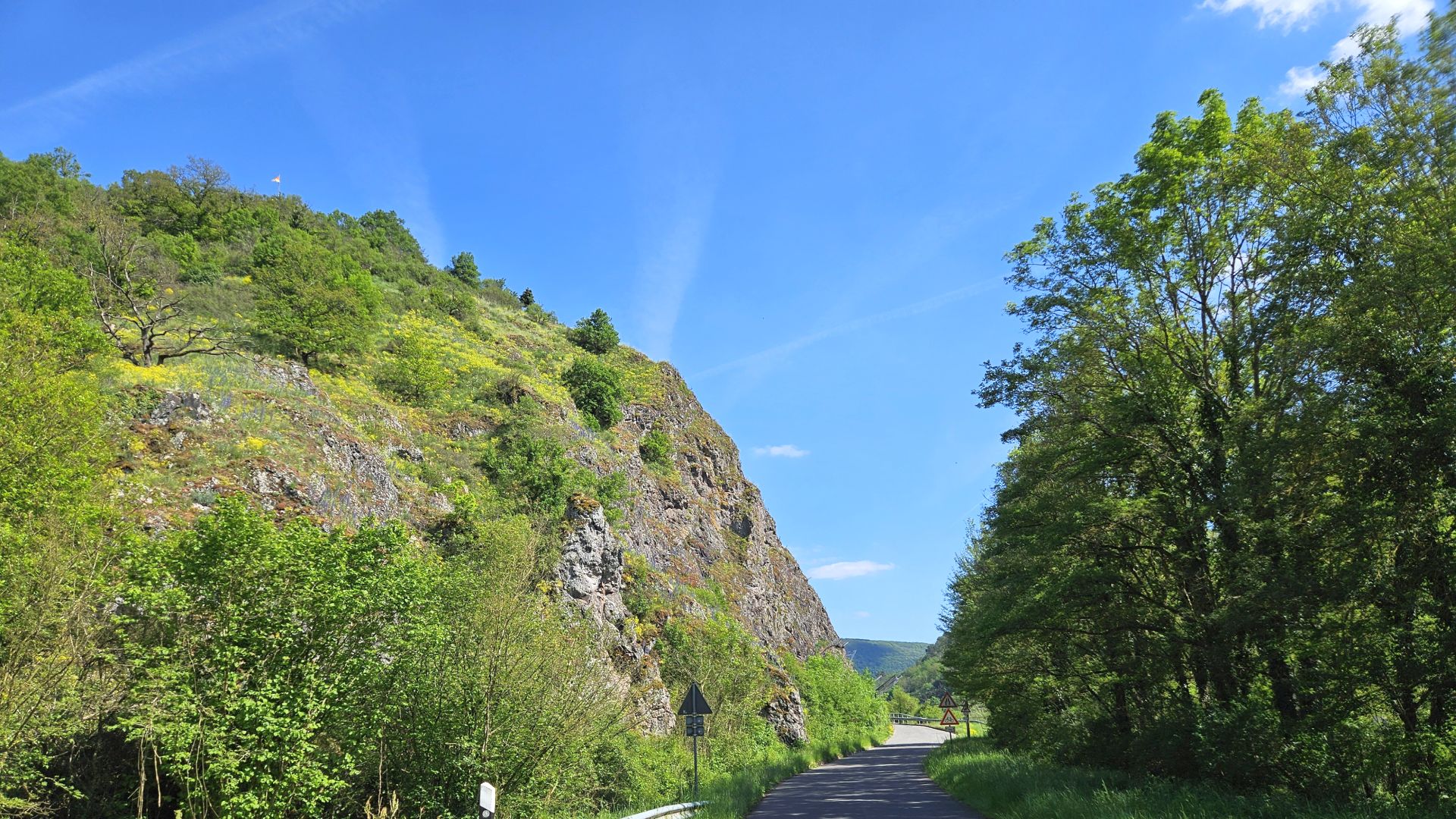 Felsige Landstraße durch grüne Hügel an einem sonnigen Sommertag