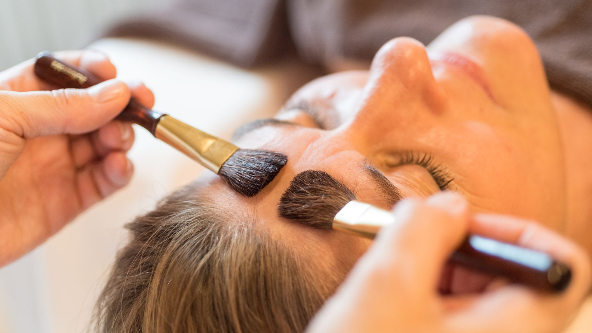 Makeup artist applying eyeshadow brushes on person's eyelids