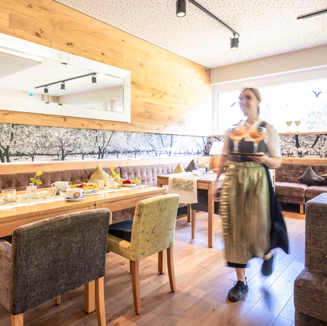 Kellnerin im Dirndl trägt Getränke in einem gemütlichen Holz-Café
