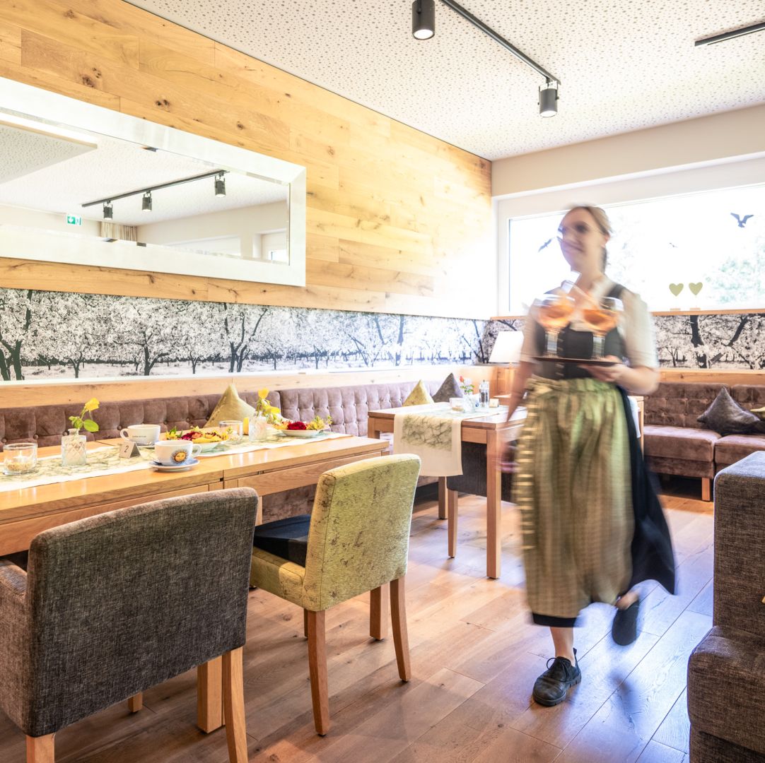 Kellnerin im Dirndl trägt Getränke in einem gemütlichen Holz-Café
