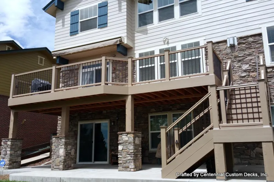 Second-story deck with tan railings, lattice-screened stairs and stone accents