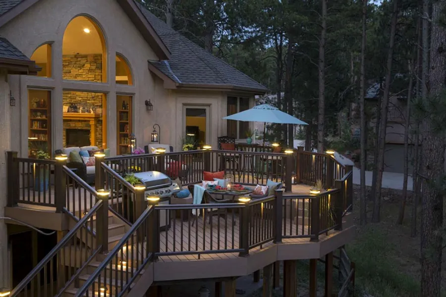 Multi-level deck with post-cap lighting and an outdoor dining area at dusk