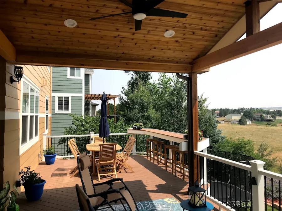 Covered deck with a dining set and patio umbrella overlooking an open field