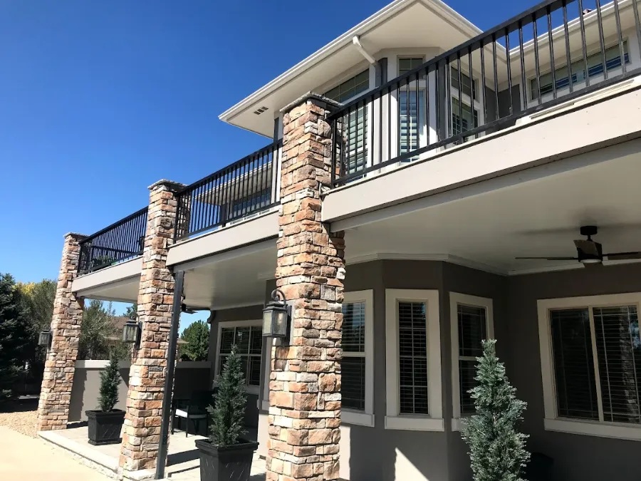 Elevated deck with black metal railings and stone-clad support columns