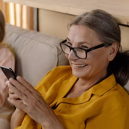 Smiling elderly woman using her cell phone to participate in an Amnesty International online vote.