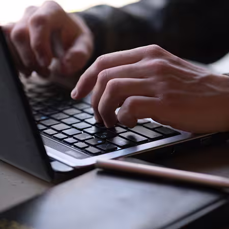 Manos tecleando en un portátil, ilustrando el caso del Ayuntamiento de Logroño sobre más participación y seguridad en los presupuestos participativos con Kuorum