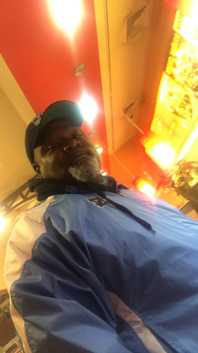 A middle aged man in a baseball hat is looking at the camera