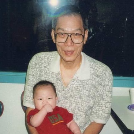 Grandpa with glasses holding infant baby in his lap