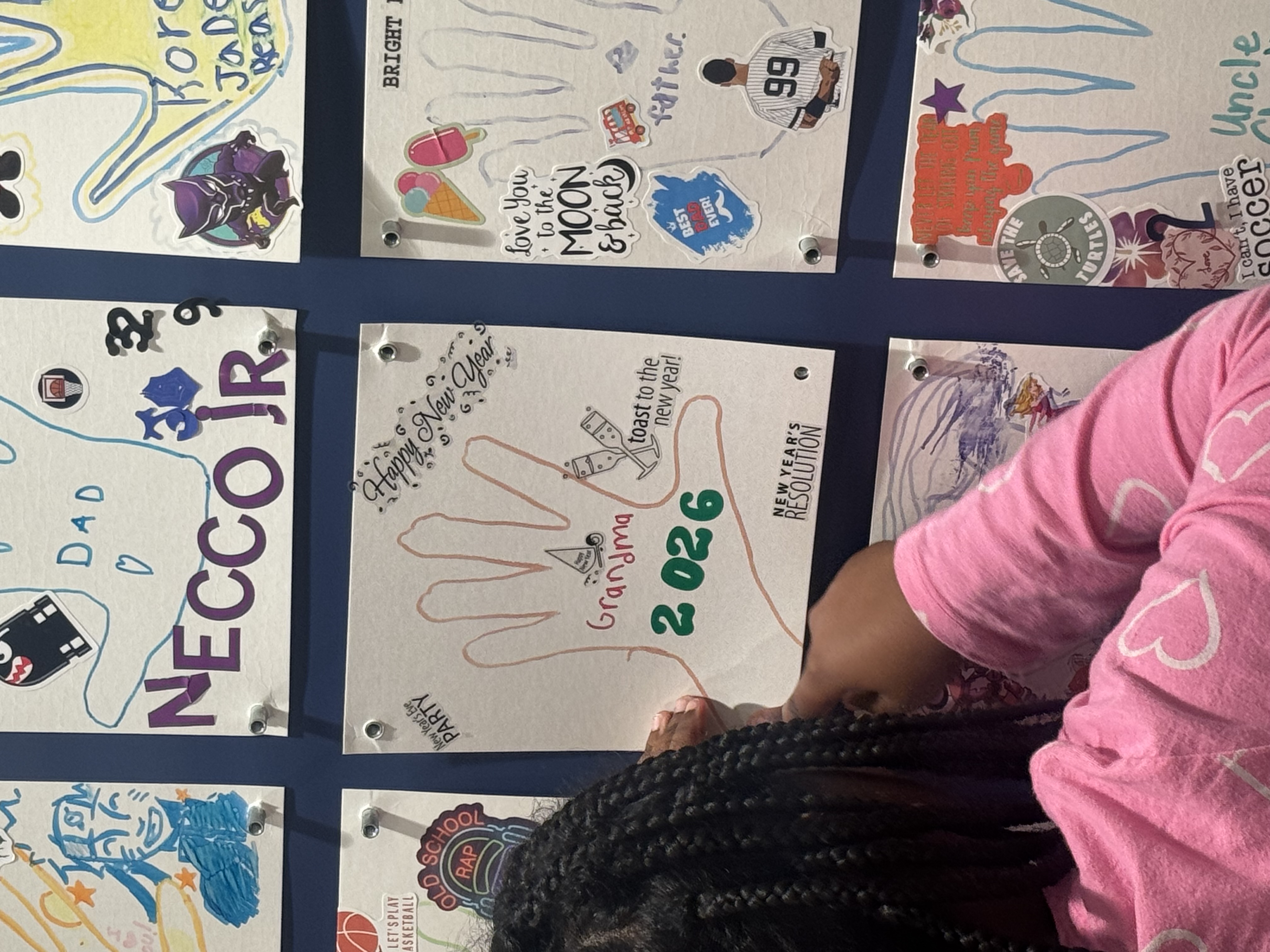 Wall of large tiles decorated in memory of people who died, girl hanging her tile up