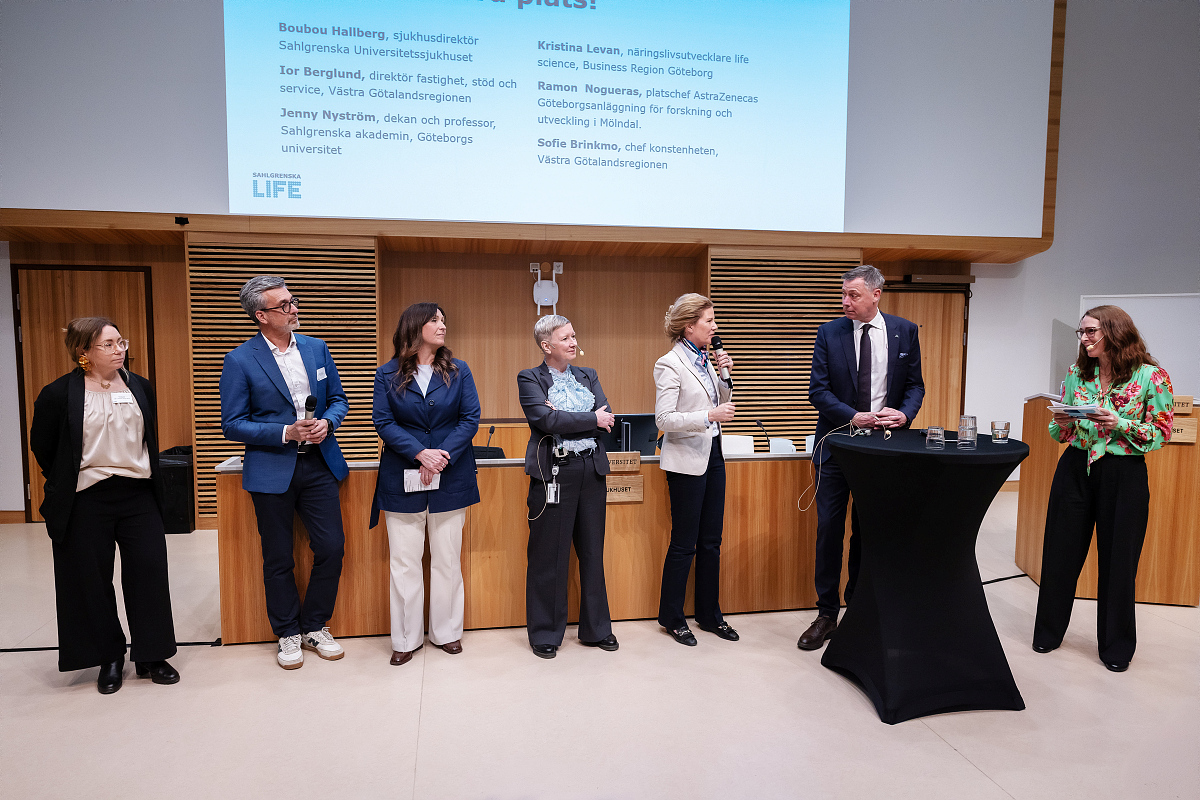 Flera personer som står längst fram i en stor aula. 