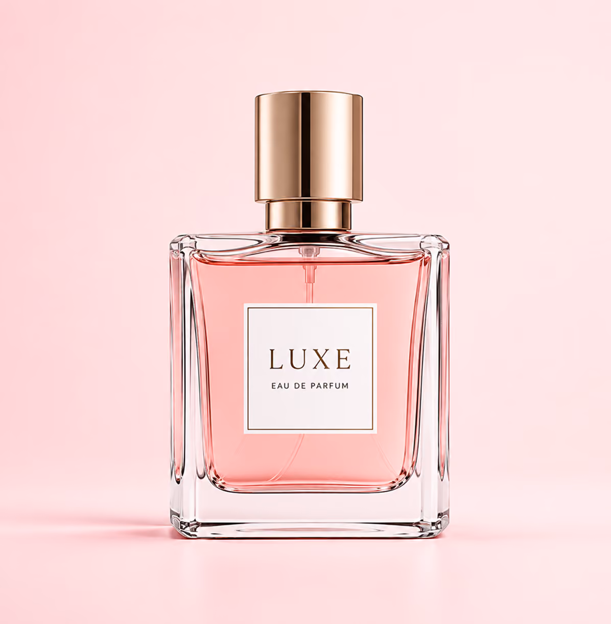 Square glass perfume bottle with pink liquid and gold cap labeled Luxe Eau De Parfum.