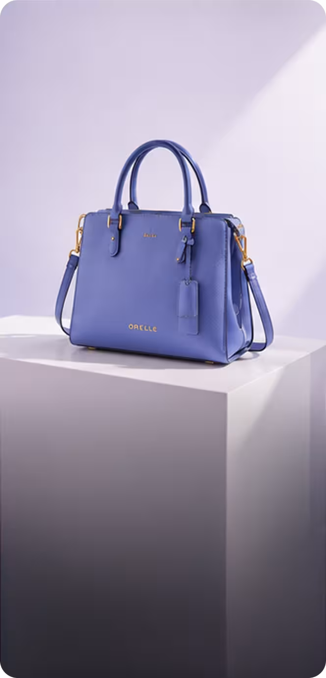 Elegant blue leather handbag with top handles and shoulder strap on white pedestal.