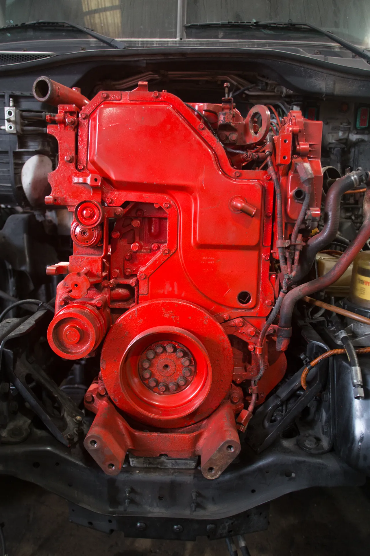 Engine replacement with a freshly painted red block installed in a heavy-duty truck chassis.