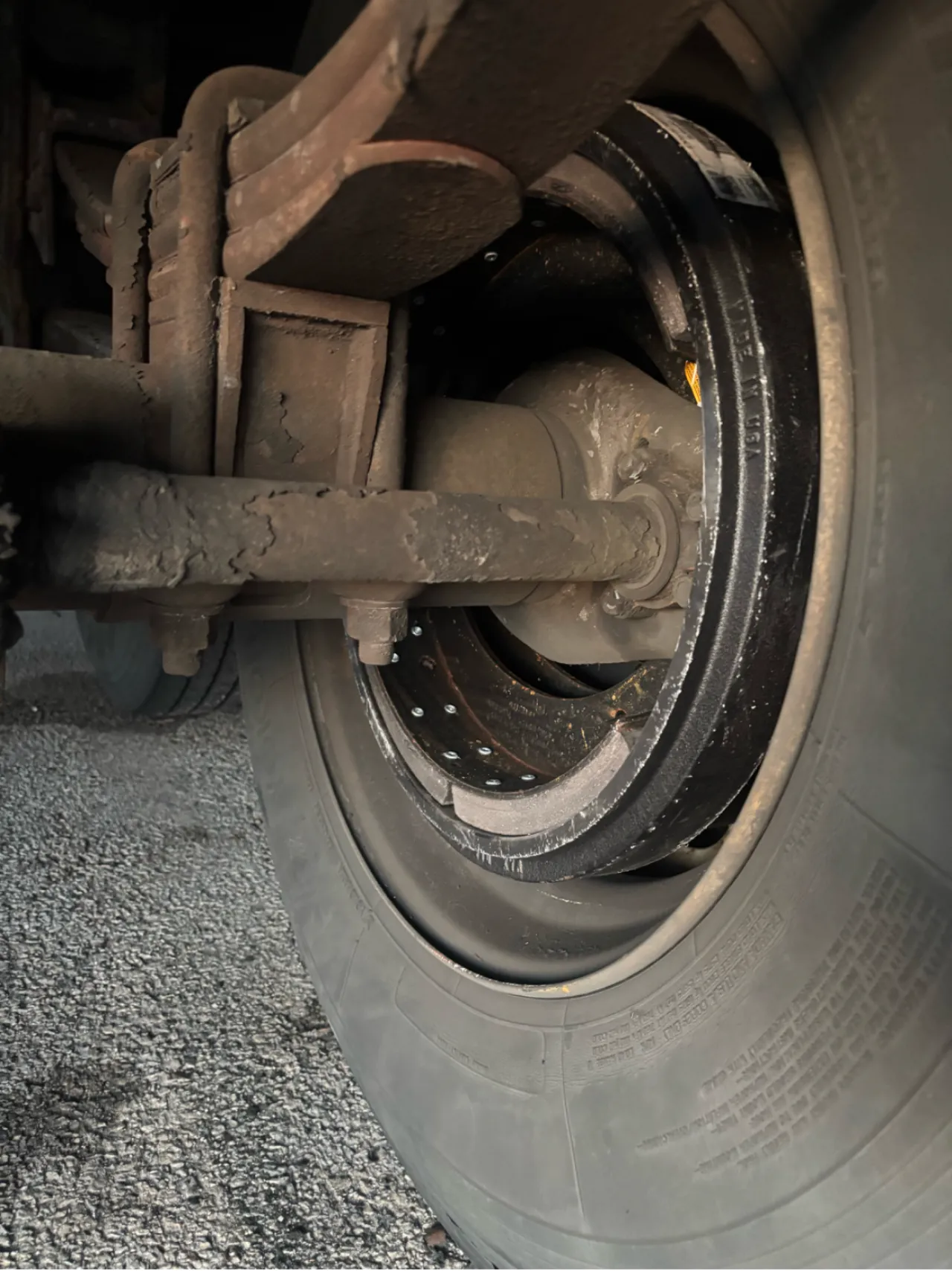 Brake drum inspection showing worn suspension components and dust buildup around the wheel assembly.