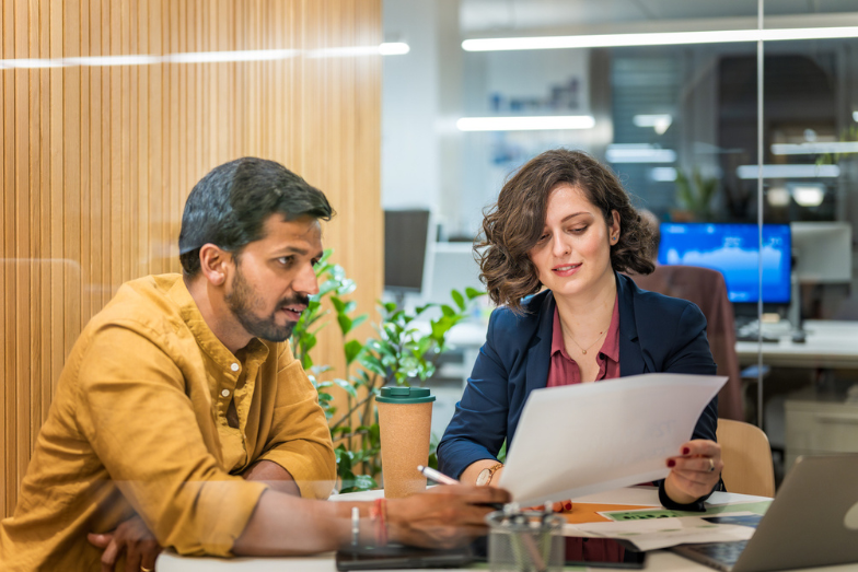 Two colleagues are looking at a document and discussing it together at the Altis Toronto office.