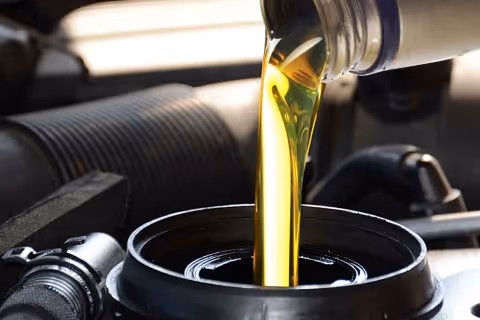 Motor oil being poured into a car engine during an oil change.