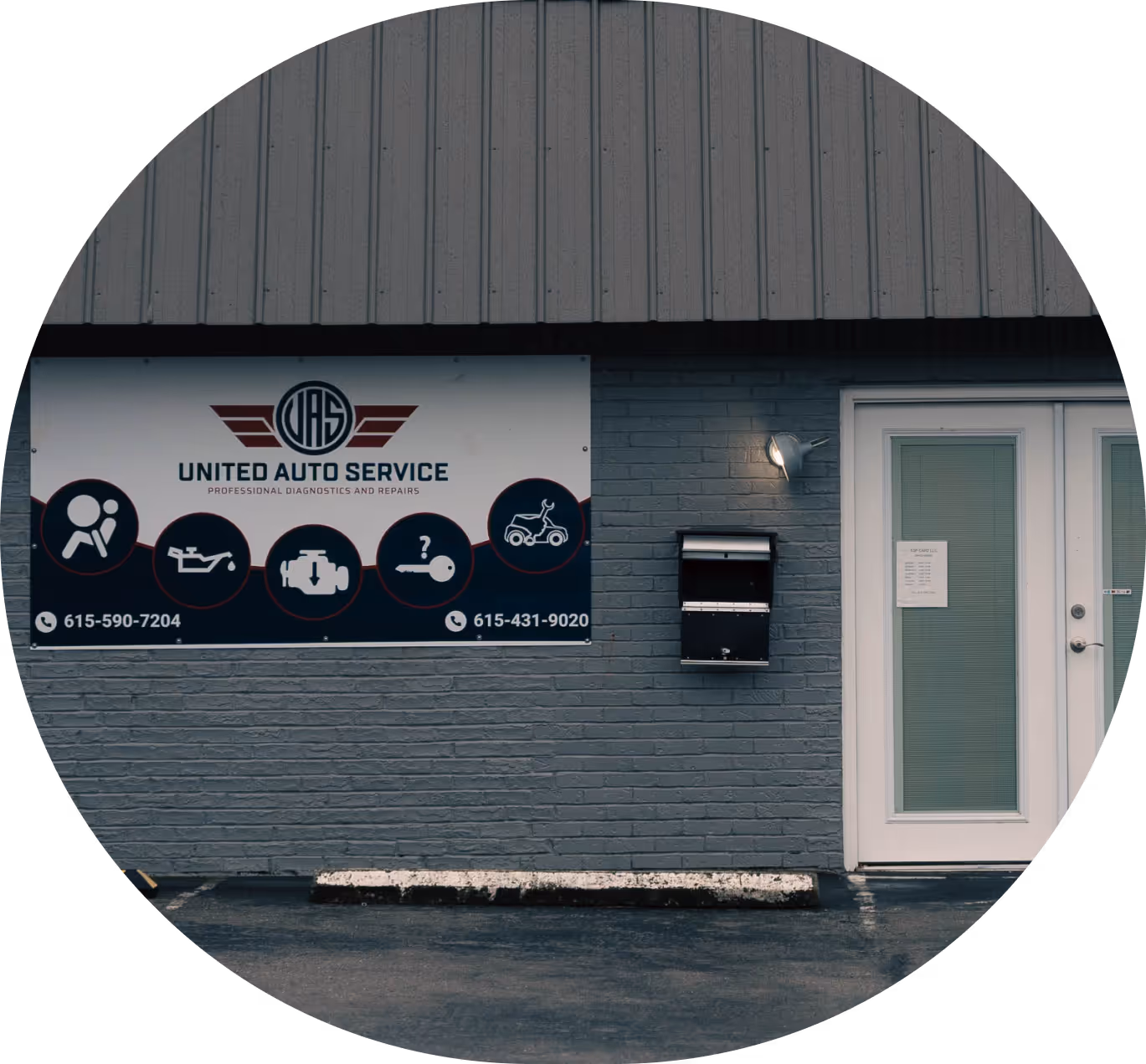 Front wall of United Auto Service shop showing logo, contact numbers, service icons, a mailbox, outdoor light, and glass double doors.