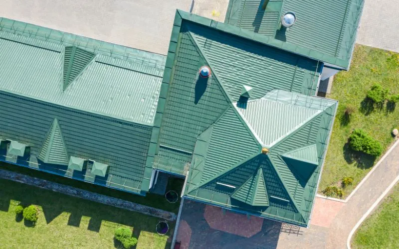 An aerial view of a metal roof surrounded by a lush green lawn