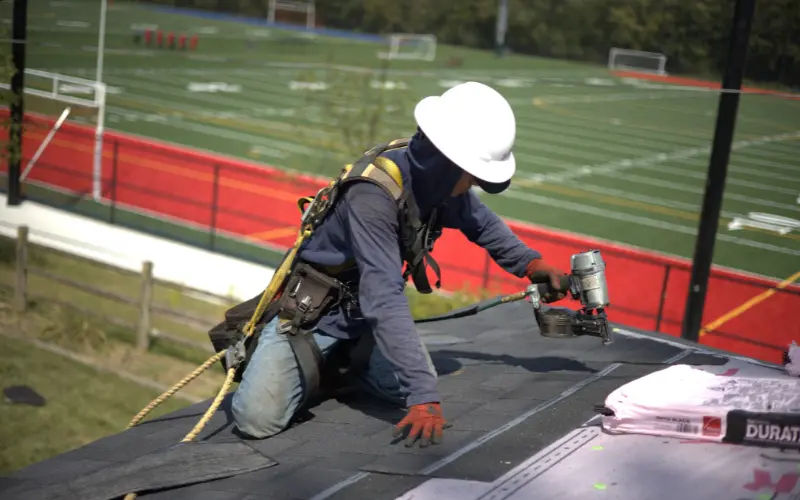 Roofer Installing Shingles On Residential Roof