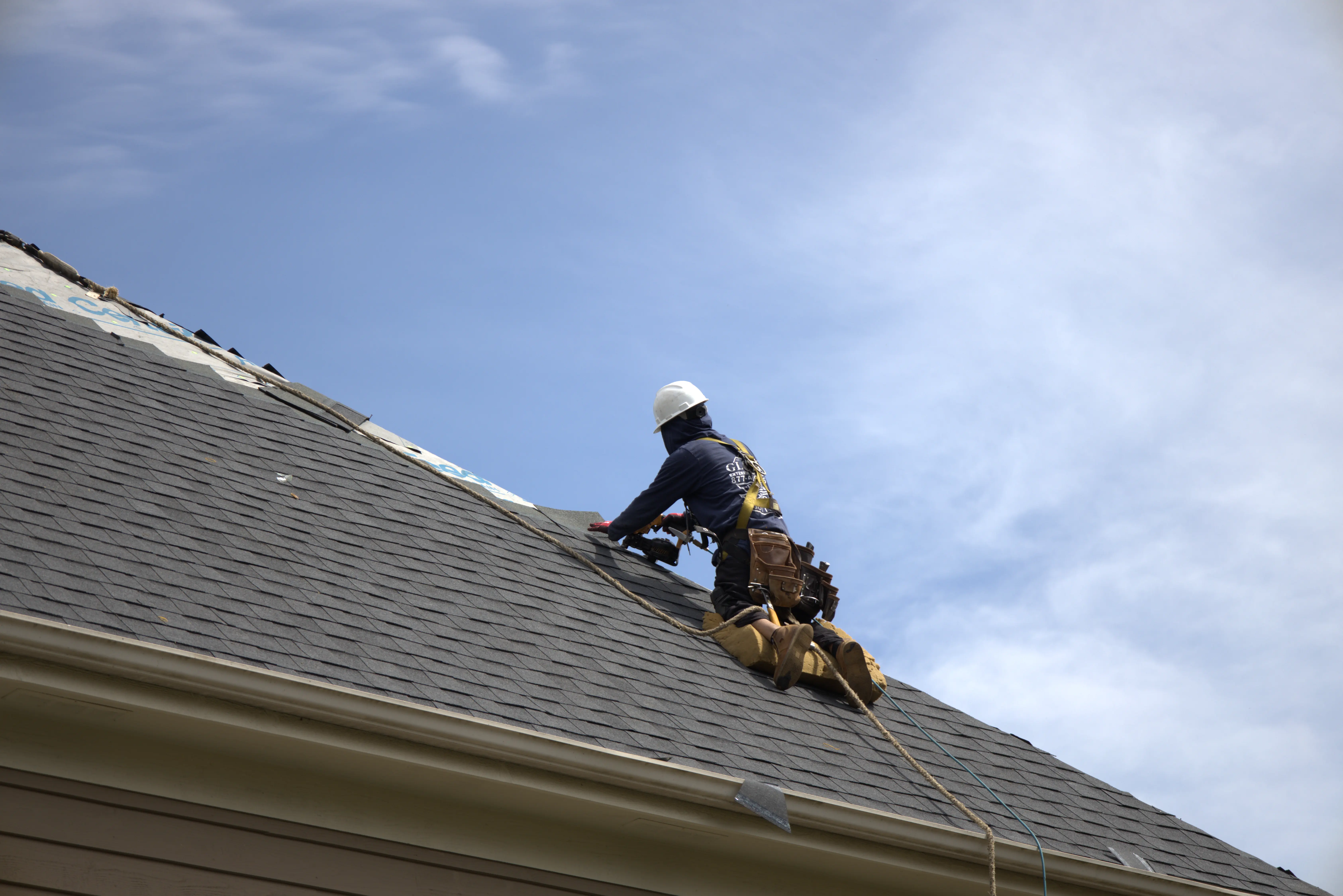 Roofer Installing Shingle Roof With full harness & protection.