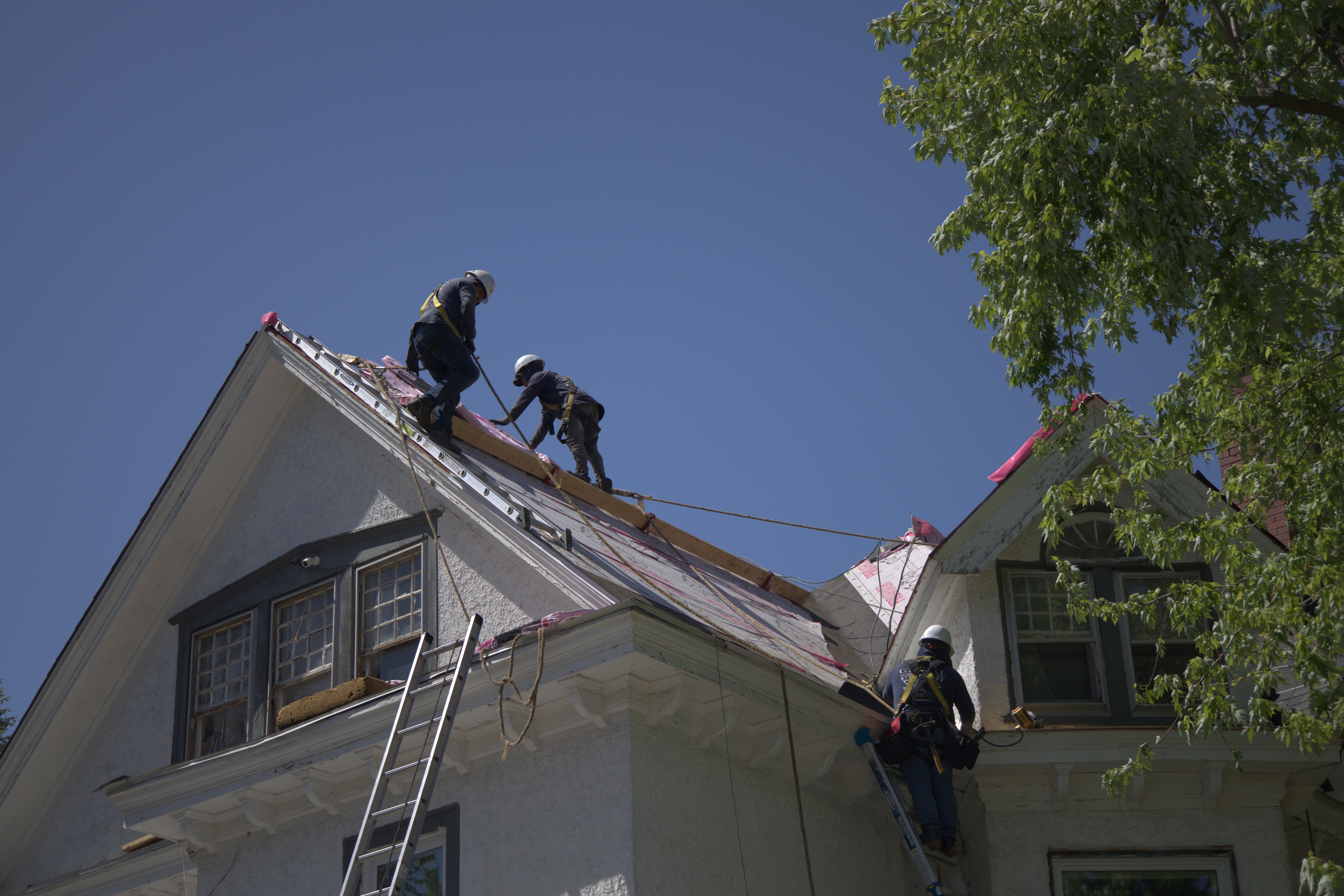 Four Roofers On Tall Steep Roof Installing Shingles