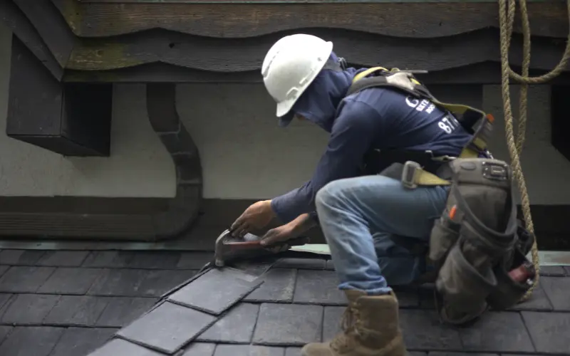 Roofer Installing Slate Roof With Hammer