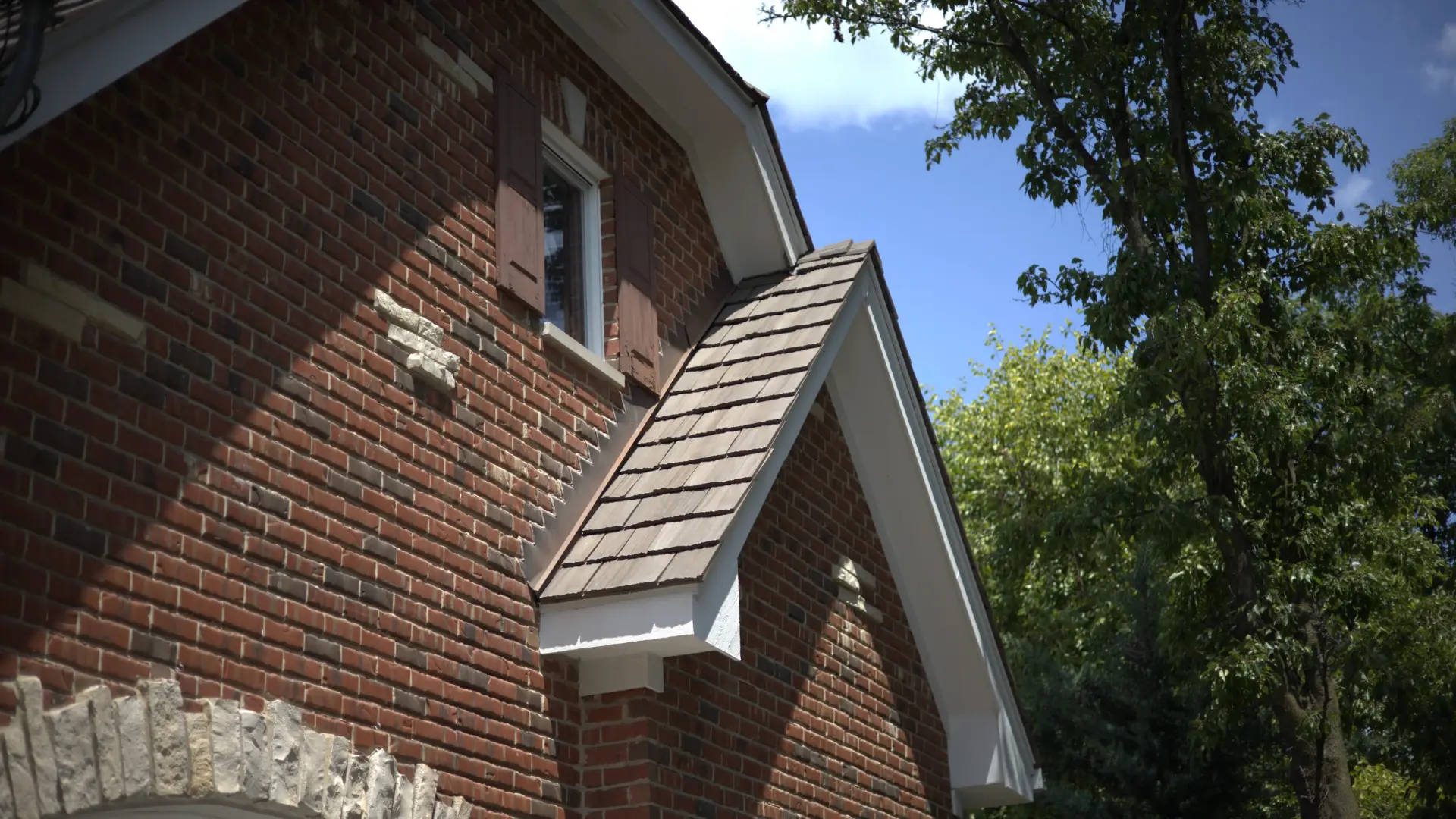 Residential Roof With Composite Shake Installed With Step Flashing On Brick Wall