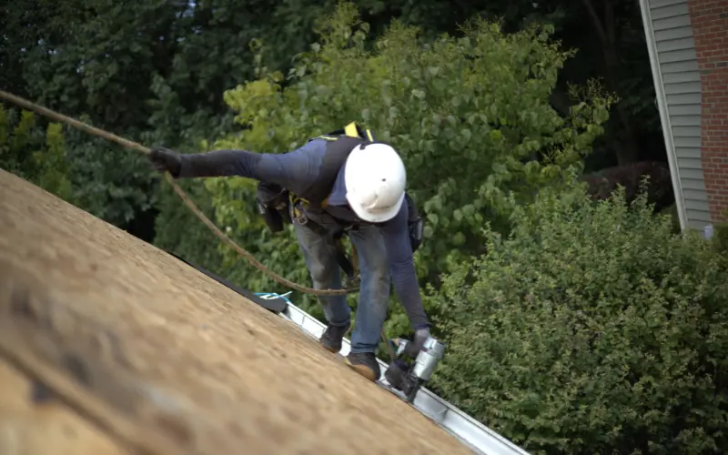 Professional Roofer Nailing In Drip Edge On Residential Home 