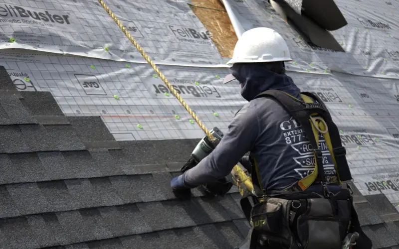 Roofer Installing Asphalt Shingle Roof With Proper Safety Equipment