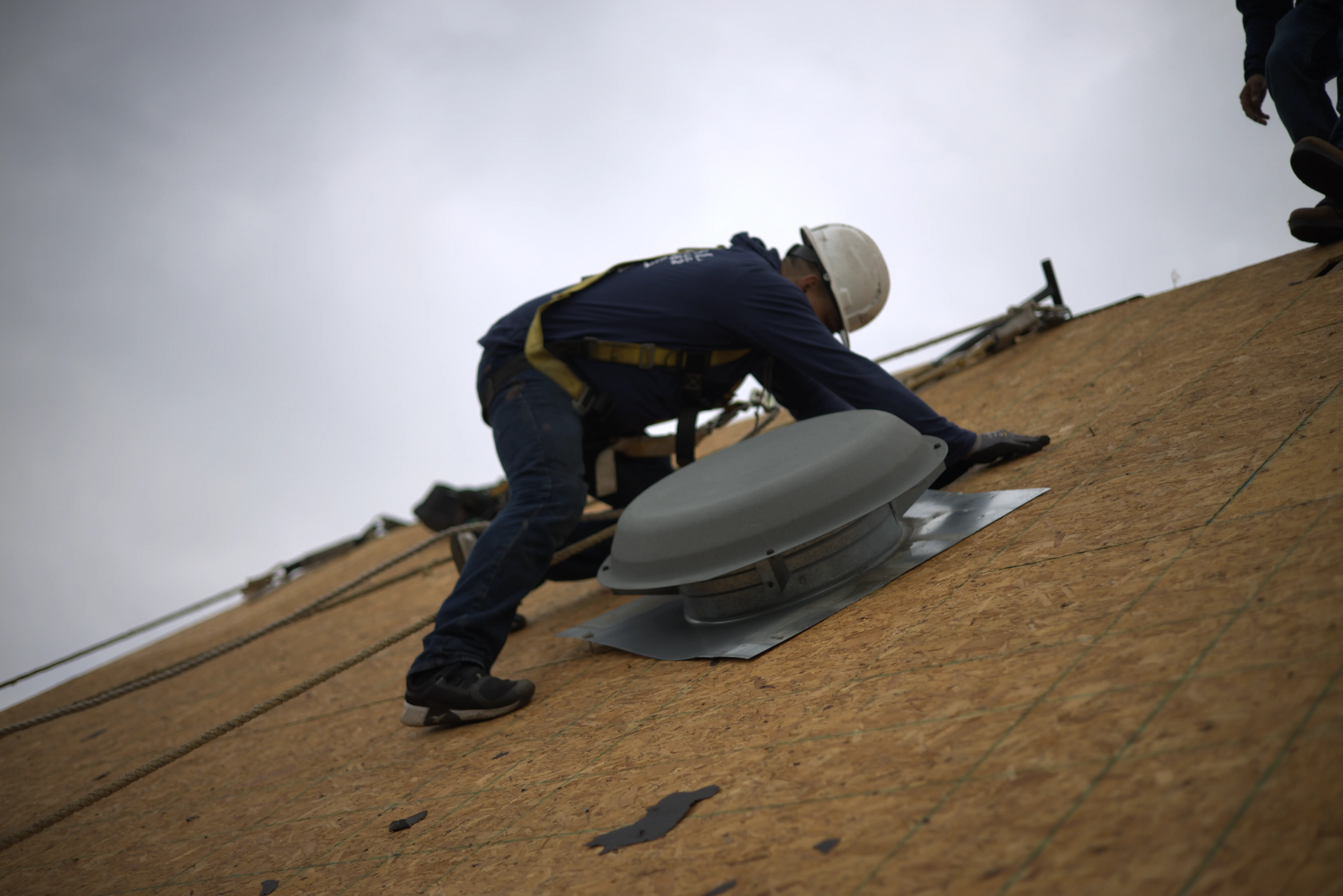 Professional Roofer With Big Mushroom Vent Next To Him