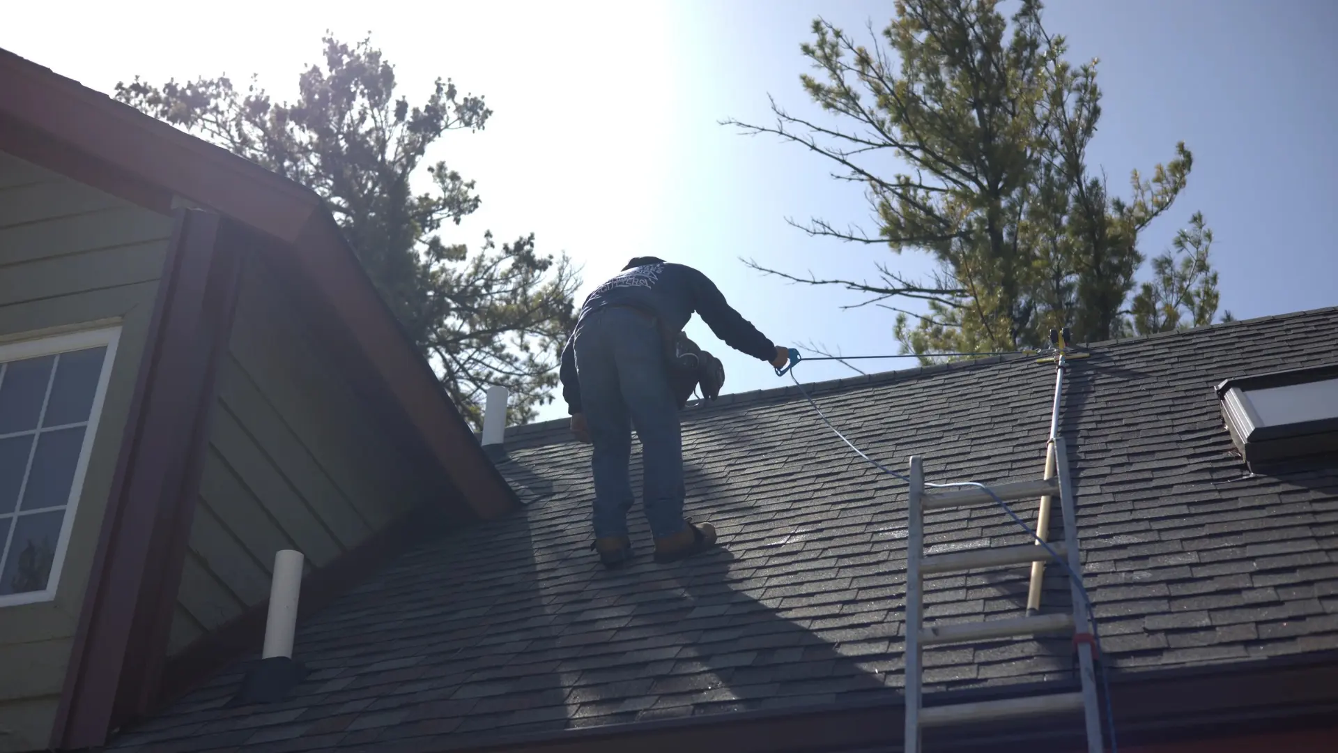 Aaron on a roof holding onto a rope