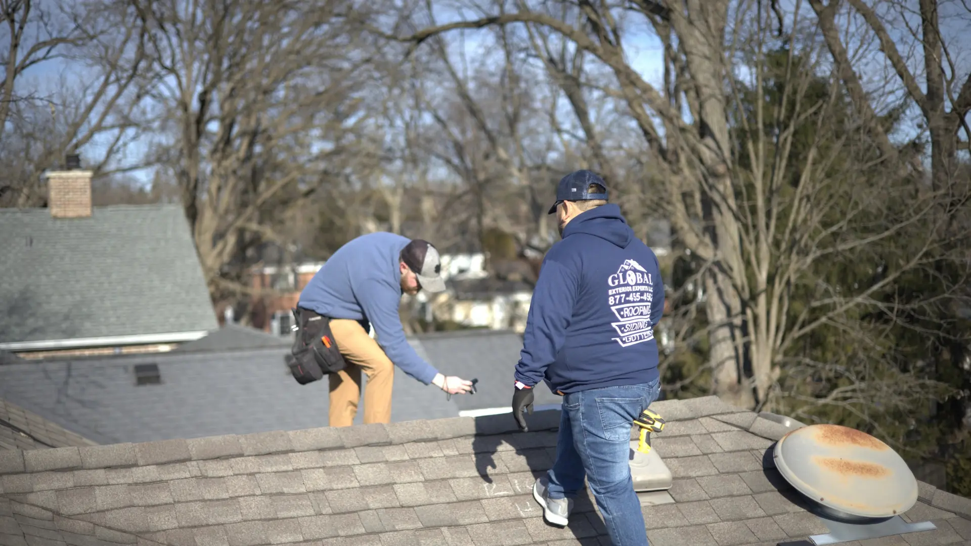 Professionals standing on roof documenting damage from hail storm