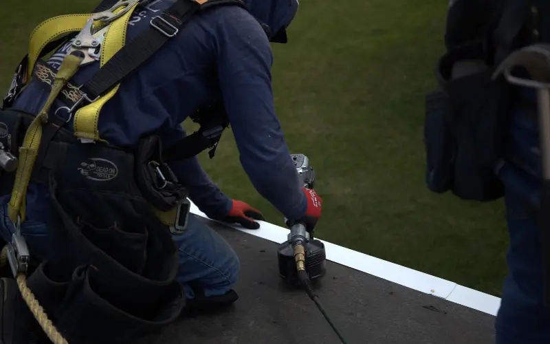 Professional roofer installing ice and water shield on residential property