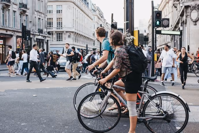 Cyclists waiting for traffic lights on Oxford Street near entrance to Oxford Circus tube station