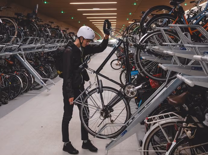 Cyclist securing bicycle at Dutch cycle storage facility