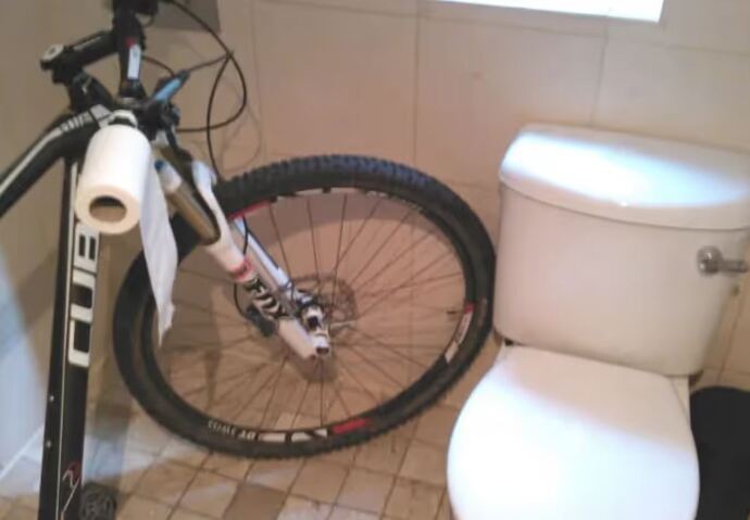 mountain bike stored in small bathroom with its handlebar doubling up as a loo roll holder