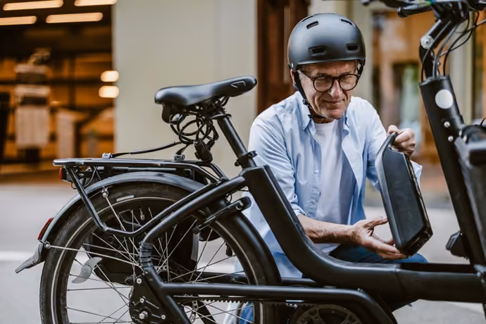 man removing battery pack from e-bike parked on UK street