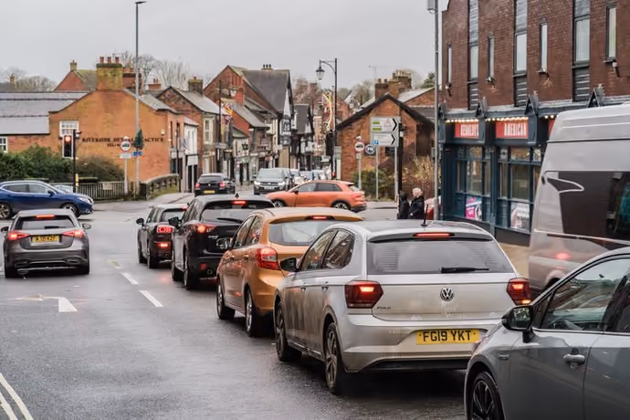 queue of cars waiting at red light on UK street