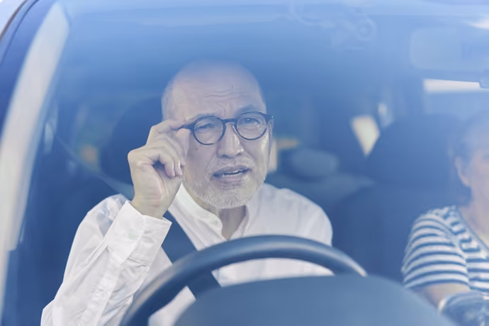 older driver wearing spectacles at the wheel of a car