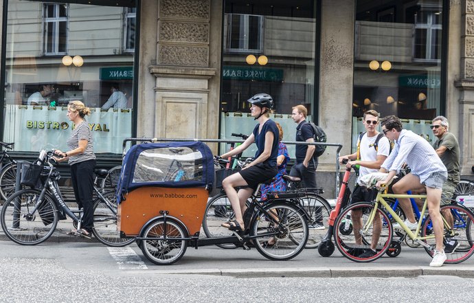 Street with people on bicycles and a Babboe cargo bike waiting at a red light